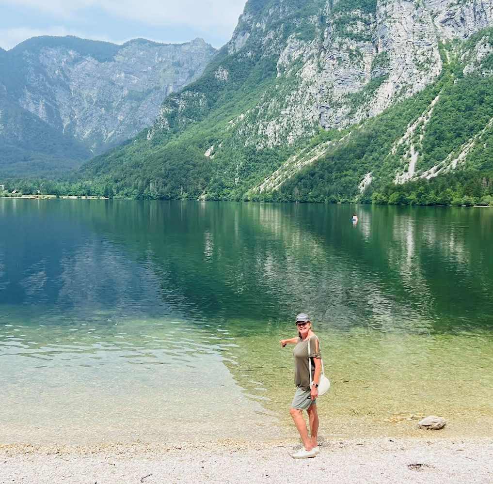 Robin pointing to the fish swimming in shallow water at Lake Bohinj, Slovenia